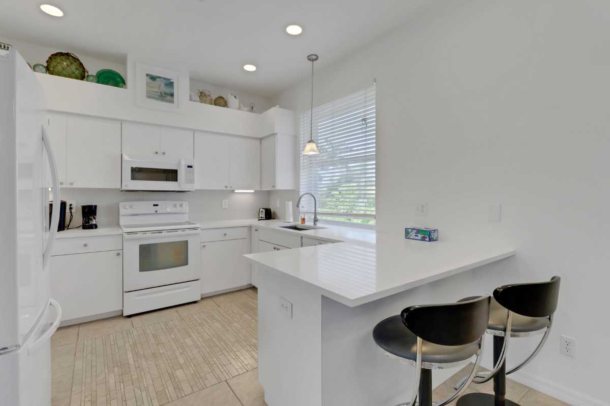 A beautiful kitchen with white cabinets and white quartz counters in a house for sale.